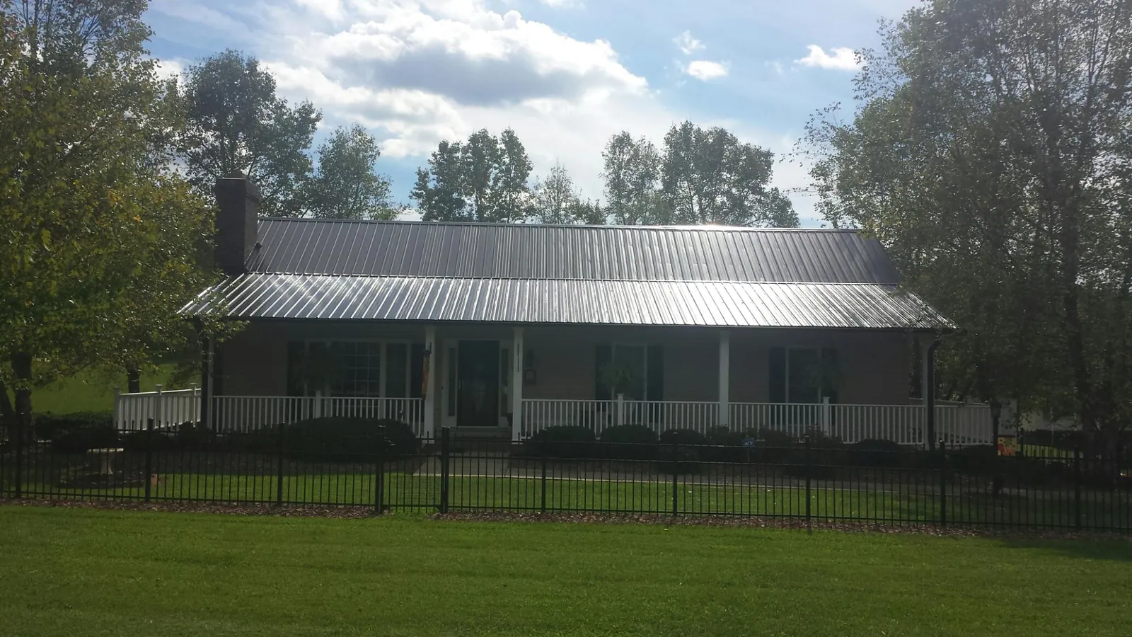 Gray metal roof on a brick ranch with a full width front porch — Gutter Guard Installation work by our crew in Riverdale
